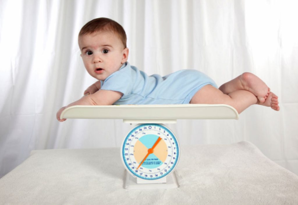 An infant weighing his weight with salter baby scale