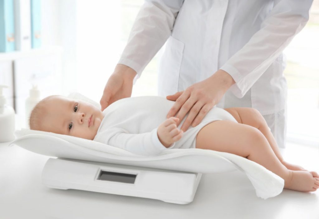 a doctor weighing a baby with a newborn baby scale