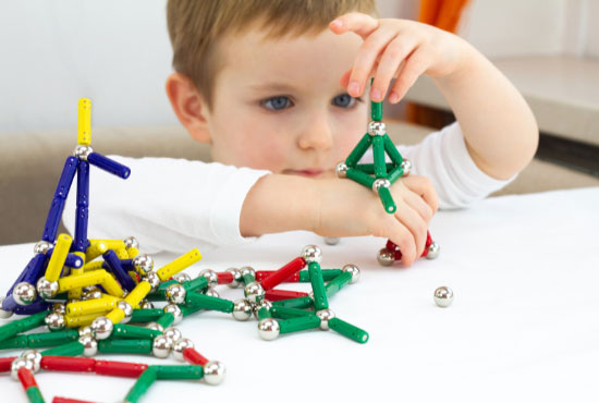 Cute little child boy playing magnets toy for brain development