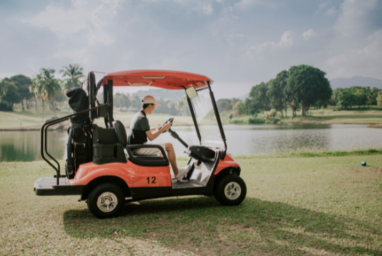 a boy driving golf buggy in the golf course